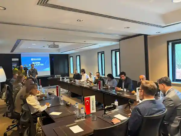 Toplantı masası etrafında enerji basını temsilcileri ve EDEDER yöneticileri, mikrofonlar ve bayraklar